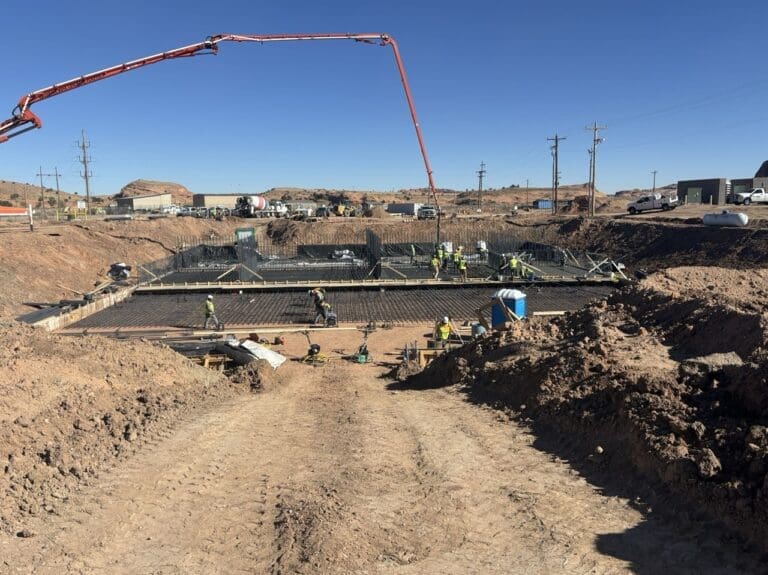 Large concrete slab foundation with rebar grid installation and concrete pump in operation at Kayenta AZ Waste Water Treatment Plant