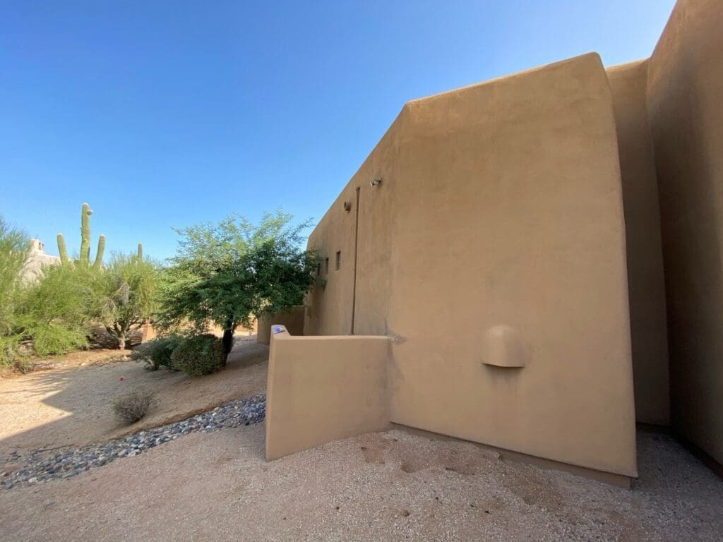 Exterior view of the existing stucco wall and landscape area before the home addition