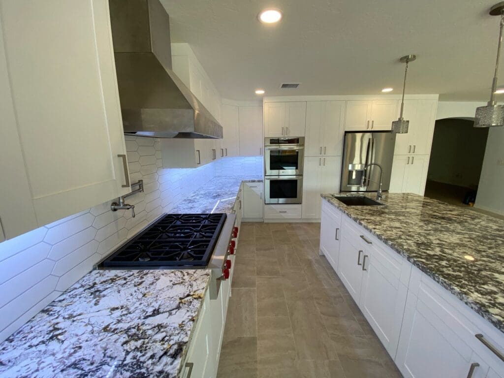Side view of upgraded kitchen with granite counters, white cabinets, and stainless steel appliances