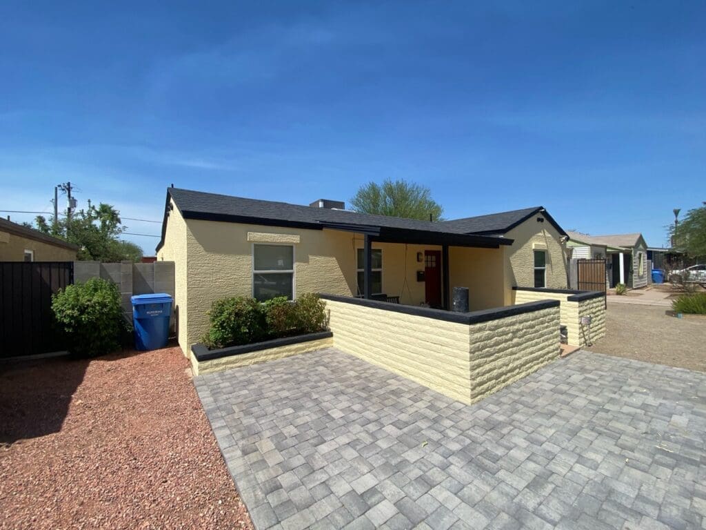 Front exterior of remodeled Phoenix home with new paver driveway, yellow stucco walls, and covered entry porch